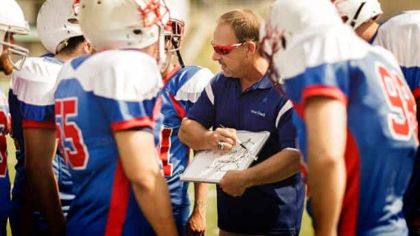 Coaching drawing up plays for football team