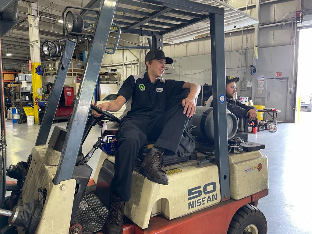 AG Automotive employee riding in forklift